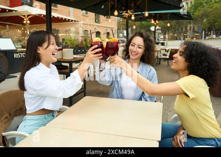 Three women are sitting at a table, laughing Stock Photo