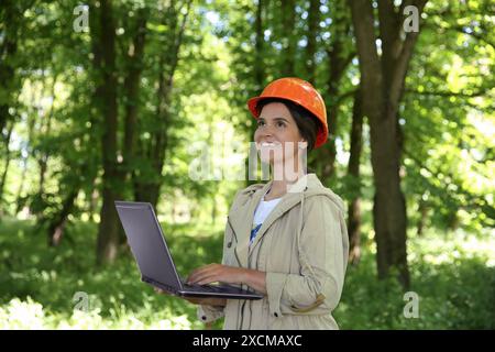 Forester with laptop examining plants in forest Stock Photo