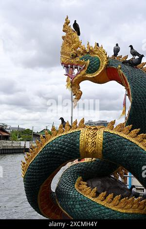 Close-up of a Naga sculpture overlooking a waterway canal in Thailand Stock Photo