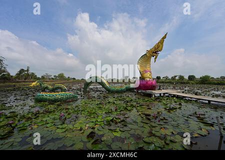 Large sculpture of a colorful giant Naga rising out of a lotus from a wetland pond, Thailand Stock Photo