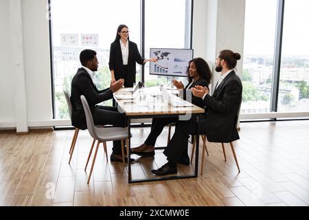 Caucasian business woman giving a presentation to diverse colleagues Stock Photo