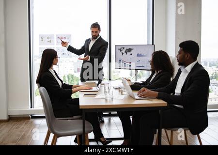 Business presentation with graphs to multiracial colleagues in modern office Stock Photo