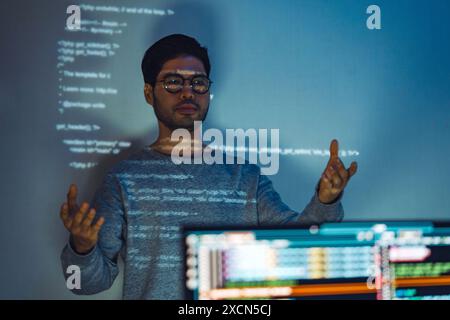 Indian man programmer standing in front of a screen with code projected  presentation the integration of technology and human expertise in software de Stock Photo