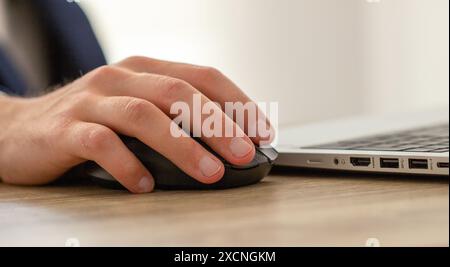 male hand on a computer mouse, workplace with laptop Stock Photo