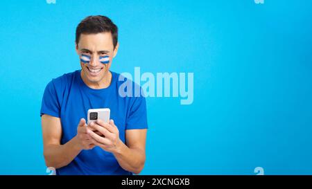 Salvadoran supporter looking at his mobile smiling and showing it. Stock Photo