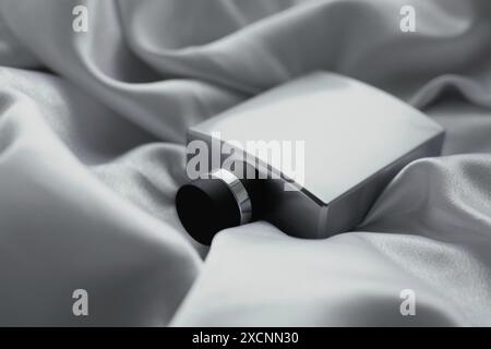 Bottle of green perfume on white silk Stock Photo