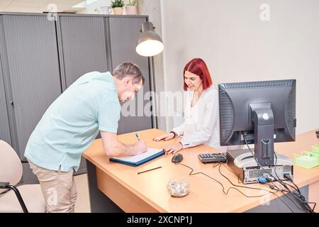 man signing at the reception desk of the clinic Stock Photo