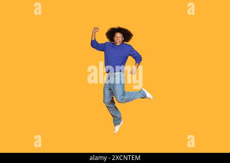 Happy Man Jumping In The Air Against Yellow Background Stock Photo