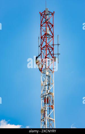 technician workers on a cellular tower antenna, clear sky background Stock Photo