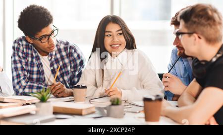 Happy multiracial college students studying with books in library Stock Photo