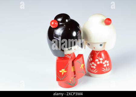 Japanese wooden dolls 'kokeshi' in red Kimono suit, toy for a decoration, souvenir from Japan Isolated on white background. Stock Photo