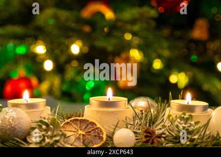 Three burning candles in front of the Christmas tree. Shallow depth of field, copy space. Stock Photo