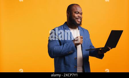 Employee does no hand gesture with finger while chatting with coworker during meeting using laptop, studio background. Person showing disagreeing sign, protesting idea during videocall, camera B Stock Photo