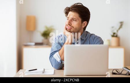 Man Contemplating at Desk With Laptop Stock Photo