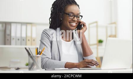 Cheerful young African American lady manager talking on phone Stock Photo