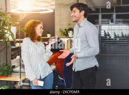 Man and Woman Standing in Office, Chatting Stock Photo