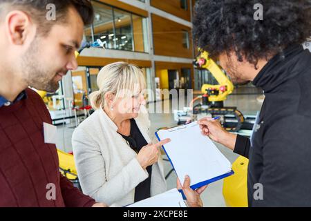 Group of engineers collaborating on robotics programming and development in an industrial environment. Highlighting process automation, teamwork, and Stock Photo