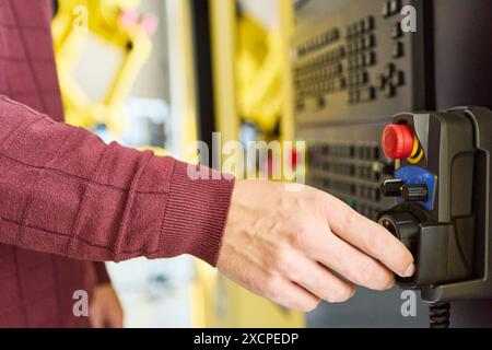 Close-up of an engineer's hand adjusting an industrial robot controller in a manufacturing setting, representing robotics, automation, and technology Stock Photo