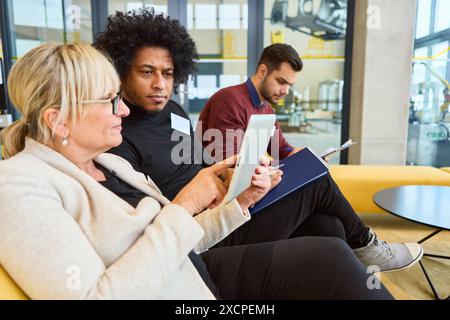 Three colleagues collaborating on robotics programming and development in a modern office space, discussing automation processes and technology innova Stock Photo