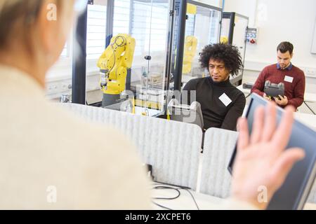 Engineers at a training session focused on programming and operating robotic arms for process automation in various industries. Stock Photo