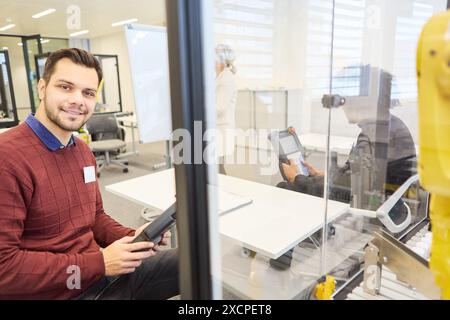 Engineers in a modern office setting, programming and working with robotic arms. Emphasizing process automation and industrial applications. Stock Photo