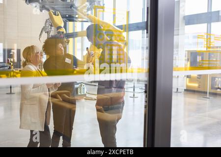 Group of engineers discussing robotics and automation in a modern industrial facility. Concept of collaborative technology, programming, and industria Stock Photo