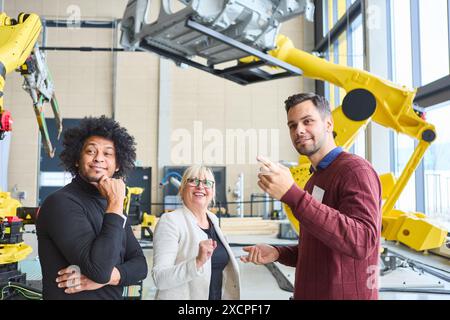 Group of engineers conversing about industrial robotics and automation, highlighting collaborative teamwork and high-tech innovation in a modern manuf Stock Photo