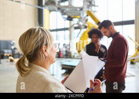 Engineers collaborating on robot programming in a modern industrial facility. Focus on automation, production, and technology in manufacturing industr Stock Photo