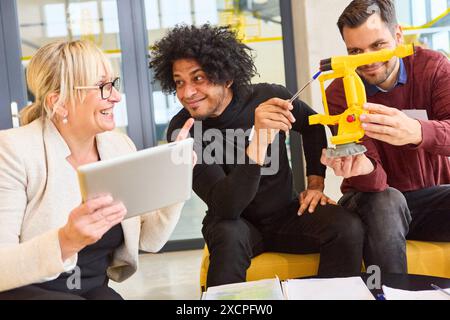 Group of professionals discussing and programming a robotic arm. Collaborative teamwork in robotics and process automation in modern office environmen Stock Photo