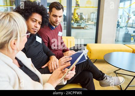 Three professionals engaged in a discussion about robotics and process automation in a modern office space. They appear focused on training and progra Stock Photo