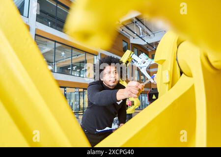 Engineer working on programming a robot equipped with a gripper arm in a contemporary industrial setting, highlighting automation and innovation. Stock Photo