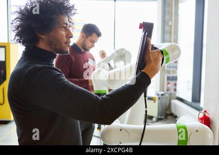 Engineers work on programming robots with gripper arms, focusing on process automation for various industries including automotive, medical, electroni Stock Photo