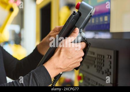 Engineer using a tablet to program and control a robotic arm for industrial applications in a technology lab environment. Stock Photo