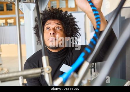 An engineer working on a robotic system with gripper arms used in industrial automation, programming and process inspection. Stock Photo