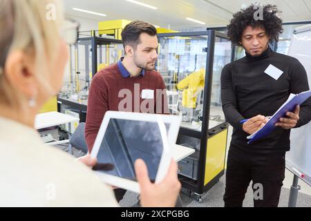 A team of engineers collaborating on robotics programming and automation tasks in a high-tech lab setting, focused on process automation and industria Stock Photo
