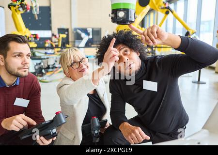 Group of engineers collaborating on programming and inspecting robotics for automation in an industrial environment. Stock Photo