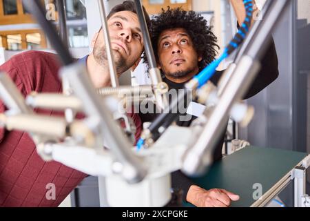 Two engineers collaborating on programming a robotic arm for industrial automation and inspection, focusing on precision and teamwork in a technical e Stock Photo