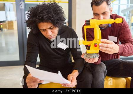 Two engineers working on the development and design of a robotic gripper arm for industrial applications, focusing on innovation, process automation, Stock Photo