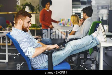 Young Man Working on Laptop in Modern Office Space Stock Photo