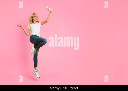 Happy Woman Taking Selfie While Jumping in the Air Stock Photo