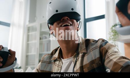 African American guy play virtual reality 3d cyber game ethnic funny amazed wonder man playing gaming wearing VR glasses helmet using joysticks future Stock Photo
