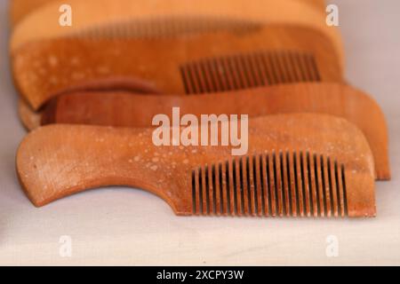 A row of wooden combs are lined up on a table. The combs are all different sizes and shapes, but they all have a similar texture and color. The scene Stock Photo