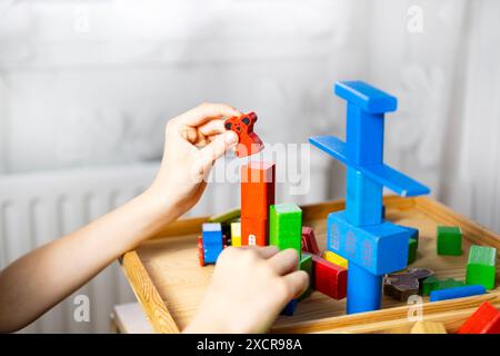 smart child, schoolboy playing with educational toy, wooden geometric figures, blocks in boy's hands, developing brain games, concept childhood, child Stock Photo