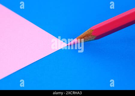 Pink pencil opening a plane of the same color on a blue background Stock Photo