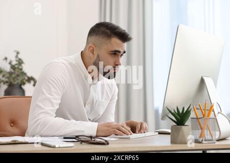 Young man with poor posture working at table in office Stock Photo