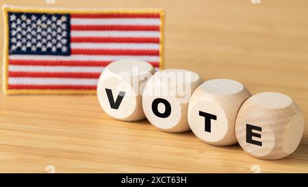 The word vote on wooden cubes and the American flag in the background. The concept of voting in the United States Stock Photo