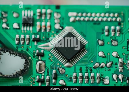 Detailed close-up green circuit board showcasing intricate electronic components, including microchips, resistors, and capacitors. Damaged printed circuit board with a hole, repair.  Stock Photo