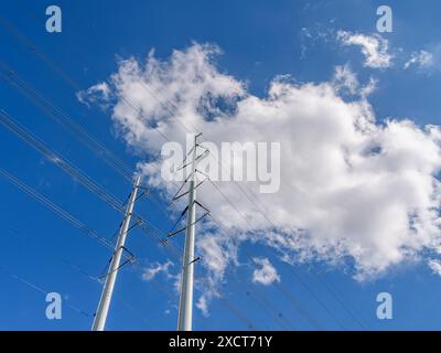 new modern electricity pylons with blue sky and clouds as background Stock Photo