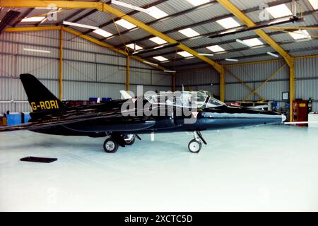 Former RAF jet trainer Folland Gnat T1 G-RORI in a hangar at North Weald, Essex, UK. Ex military Royal Air Force 1960s era jet. First flew in 1963 and served with the Royal Air Force as XR538 until 1979. Registered as G-RORI in 1993 to un-named civilian owner, then in 1997 to Bushfire Investments Ltd. In an all black colour scheme at North Weald in 1997 Stock Photo