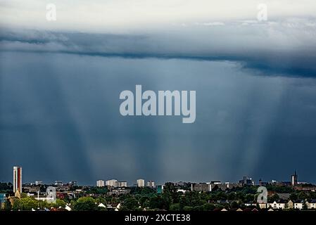 Glasgow, Scotland, UK. 18th June, 2024: UK Weather: Wet and hot sunny day in the city in the city saw strange sky  with; sunless sunbeams over the city centre skyscrapers. Credit Gerard Ferry/Alamy Live News Stock Photo